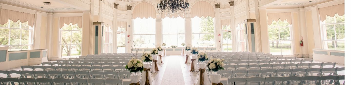 Elegant wedding venue with white chairs and floral arrangements.